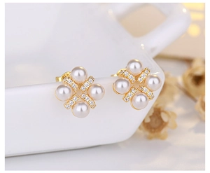 Macro shot of gold floral pearl earrings with zircon inlay on a white ceramic edge