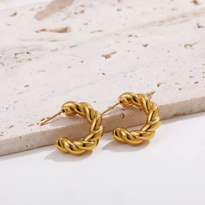 Detail of 18K gold plated C-shaped twisted rope hoop earrings with textured finish