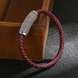 Detail of red braided leather bracelet with silver textured beads on a vintage wooden box