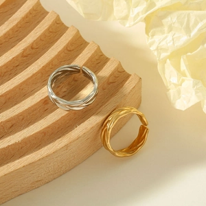 Detail of woven texture on gold and silver stainless steel rings on a wooden tray