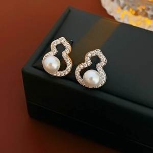 Macro shot of gold gourd-shaped stud earrings with zircon inlay and white pearls