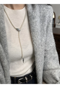 Detail of elegant pearl necklace with silver snake head clasp and green gemstone eyes