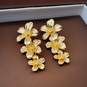 Macro detail of golden cascading flower earrings with vintage brushed metal texture