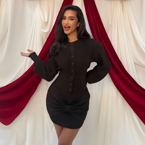 Close-up of black knit cardigan with single-breasted buttons and large bow detail on the skirt