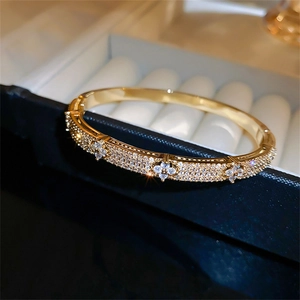 Elegant gold clover bangle with sparkling zircon pave set in a luxury jewelry box