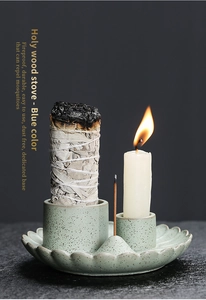 Detail of blue ceramic Palo Santo burner with white sage bundle and lit candle