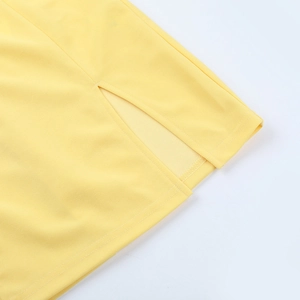 Détail macro de la fente latérale et coutures de qualité sur la robe jaune à col carré