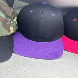Detail of a black snapback hat with a purple flat brim and ventilation eyelets