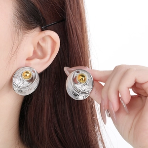 Detail shot of two-tone geometric drop earrings with silver texture and golden spheres