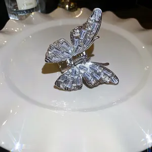 Elegant silver butterfly hair claw clip with sparkling zircon stones on a white ceramic tray