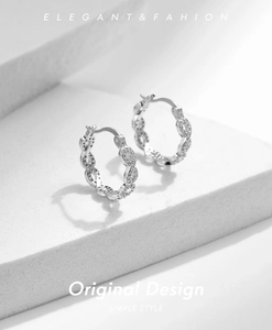 Détail de créoles Mobius en argent S925 avec design torsadé et petits diamants brillants
