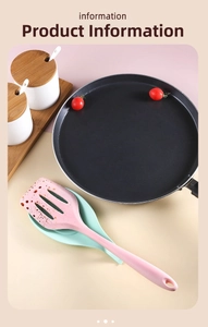 Detailed view of pink silicone turner and mint green utensil rest in a kitchen setting