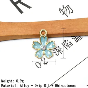 Detail of light blue enamel cherry blossom charm with gold trim and crystal center