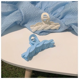 Detail of matte blue and white twisted claw clips on a white table with blue fabric