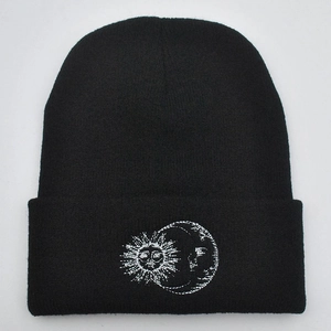 Close-up of sun and moon embroidery details on black knitted winter beanie hat