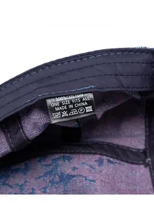 Dettaglio dell'etichetta 100% cotone e delle cuciture interne del berretto in denim