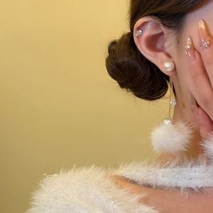 Boucles d'oreilles perles avec chaîne dorée et pendentif pompon blanc sur le mannequin