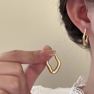 Detailed view of matte gold wavy hoop earrings showing irregular geometric texture