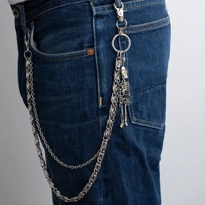Detail view of double-layered punk skull wallet chain draped on denim pants