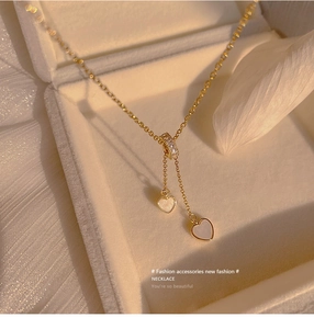 Detailaufnahme der goldenen Herz-Quasten-Halskette mit Zirkonia-Steinen in einer Box