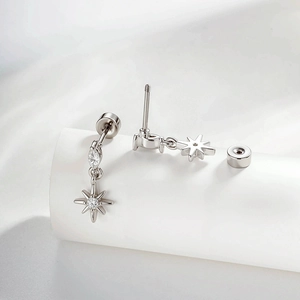 Elegant star and leaf silver stud earrings with crystals on a white pedestal