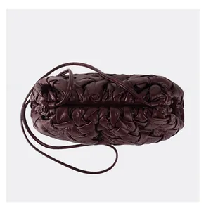 Close-up detail of burgundy woven leather bag texture and delicate matching shoulder strap