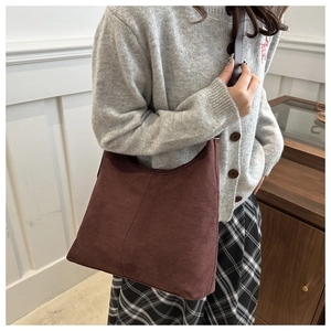 Brown frosted leather tote bag shown on shoulder in a minimalist indoor setting