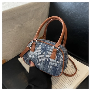 Close-up of sequined denim bag with brown leather handles on an open book