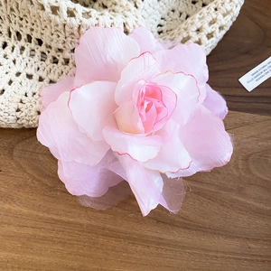 Gros plan détaillé d'une barrette fleur en maille de tissu rose sur une table