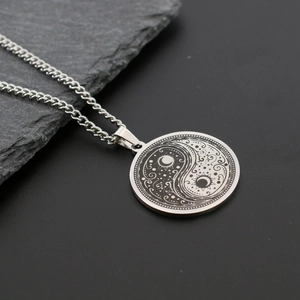 Macro view of silver titanium steel necklace pendant featuring Yin Yang and celestial motifs