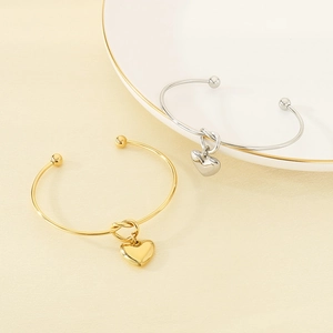 Détail des bracelets joncs ouverts en forme de C avec nœuds et pendentifs cœur en métal