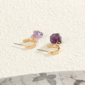 Elegant gold C-shaped earrings with purple natural stones on a white textured background