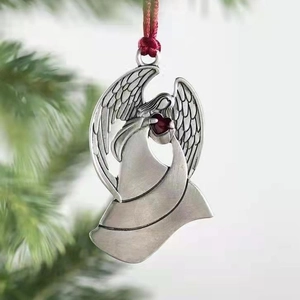 Silver metal angel ornament with red heart detail on green Christmas tree branch