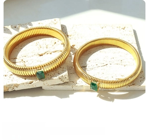 Close-up of gold-plated elastic snake bracelets with emerald-cut green zircon stones