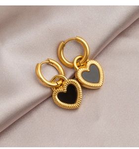 Detailed macro view of gold heart earrings with black inlay on champagne silk fabric