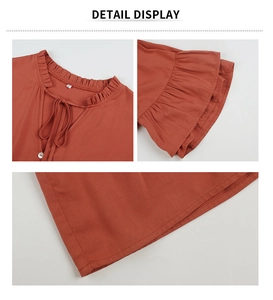 Détails de la robe orange présentant un col à volants avec laçage et bouton décoratif