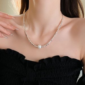 Close-up of a silver irregular bar necklace with a single pearl pendant on a model