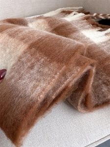 Close-up of brown and beige plaid cashmere-like scarf showing soft wool texture and fringe