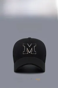 Detail of 3D embroidered letter M on a premium black cotton baseball cap with gold piping
