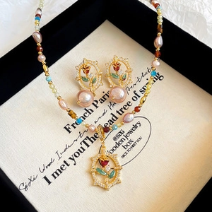 Close-up of French vintage gold jewelry set with pink pearls and red enamel rose detail