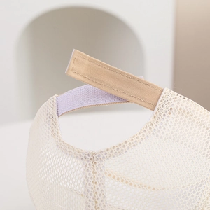 Detail view of the adjustable velcro strap and breathable mesh on the beige baby baseball cap