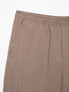 Dettaglio dei pantaloni in lino marrone caffè con vita elastica e trama del tessuto