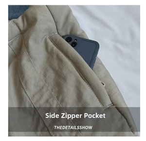Detail of side zipper pocket on khaki nylon tote bag with phone for size reference