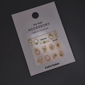 3D metallic gold nail art charms set with green and white rhinestones on display card