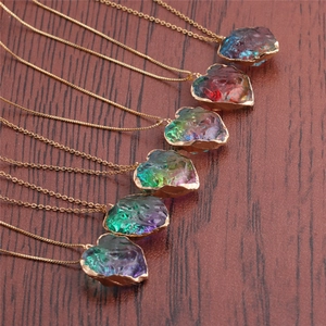 Set of six colorful heart crystal necklaces with gold chains on a dark wood background