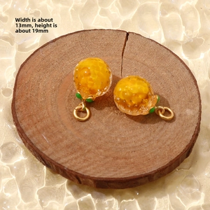 Macro detail of an orange fruit charm with green leaf and size specs 13mm by 19mm