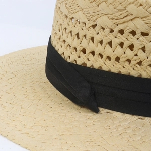 Detail of hand-woven straw hat showing breathable hollow-out texture and black ribbon