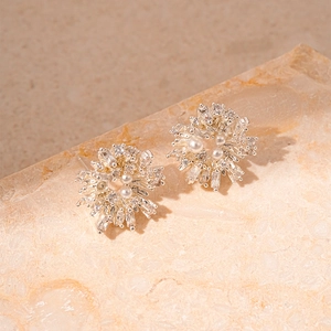 Dettaglio di orecchini a fiore in argento con zirconi e perle su pietra naturale