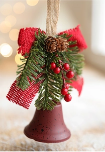 Close-up of matte red metal bell with pine cones and red linen bow for Christmas decor