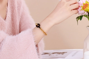 Vue détaillée d'un bracelet vintage en chaîne dorée et résine noire sur un poignet féminin